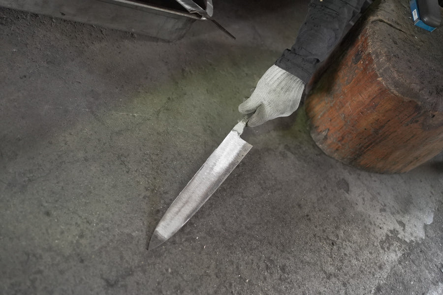 A freshly forged single-bevel blade on the workshop floor.