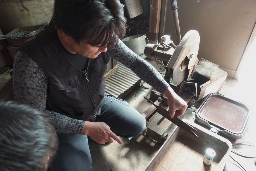 Shigeki Tanaka grinding a blade on the belt grinder in his Miki workshop, 2019